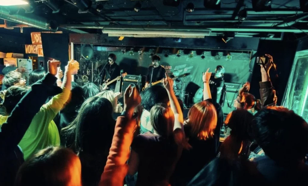 Indie artists influencing K-pop sounds performing at an underground venue with an energetic audience in Seoul's live music scene