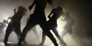 K-pop choreographies showcase dynamic synchronized dance formations during a dramatic performance with atmospheric lighting
