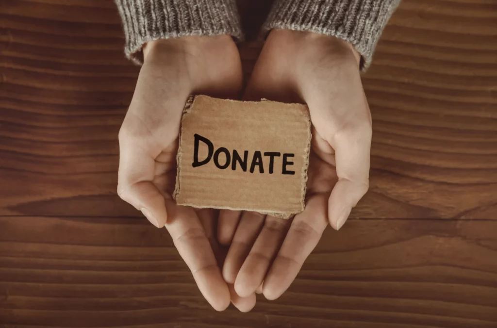 Hands holding 'DONATE' card symbolizing Korean celebrity donations culture and philanthropic impact