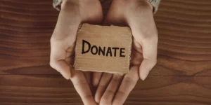 Hands holding 'DONATE' card symbolizing Korean celebrity donations culture and philanthropic impact