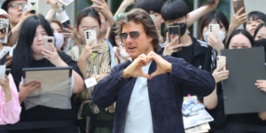 Tom Cruise making heart gesture during Korea Visit for Mission Impossible 8 while surrounded by enthusiastic Korean fans taking photos