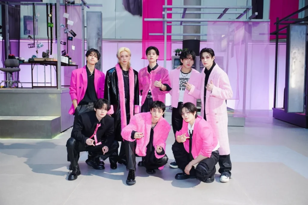 
Stray Kids members dressed in vibrant pink and black outfits representing their status as the most successful 21st century groups with eight Billboard 200 number one albums